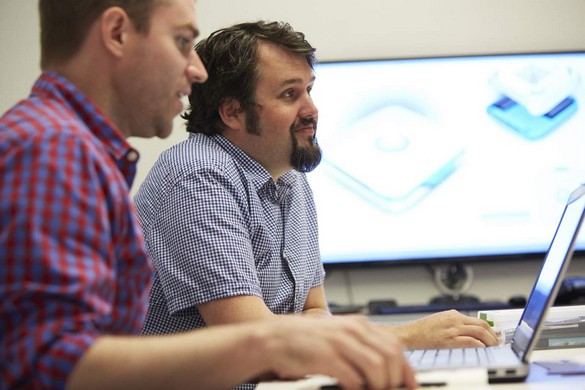 Two male engineers seated at a conference table for a meeting, one using a Dell Precision M2800 mobile workstation.