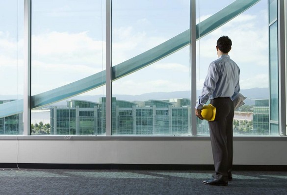 Architect looking out window of high rise building.