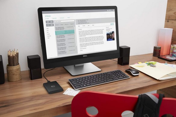 Dell Inspiron 24 5000 Series (Model 5459 Sunflower) Touch All-in-One desktop computer with KM714 (Tangerine) wireless keyboard and mouse, AC411 (Eagles) desktop multimedia speakers, and Dell External Portable 1 TB Hard Drive (Model PDB1000A), in an empty home office on a wooden desk.