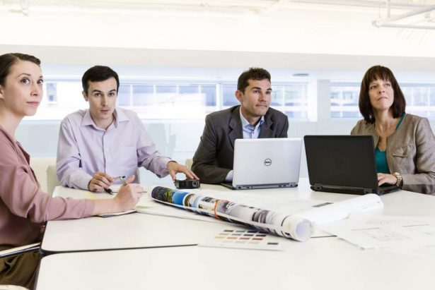 Businesspeople in Conference with Latitude E5440 and Latitutde E7440 Non-Touch notebook computers. M115 HD Mobile Projector also present.
