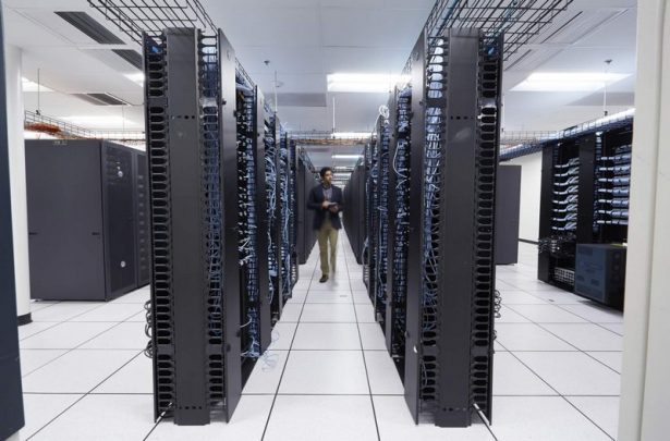 Man Walking in a Large Data Center, Using Venue Tablet